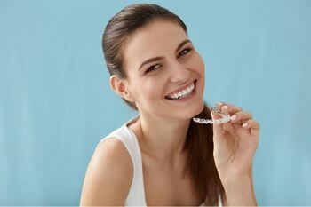 Woman smiling holding her invisalign braces in Wolverhampton