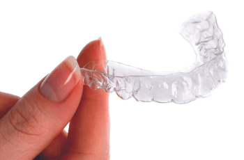 Woman holding an Invisalign aligner at Wolverhampton dental practice