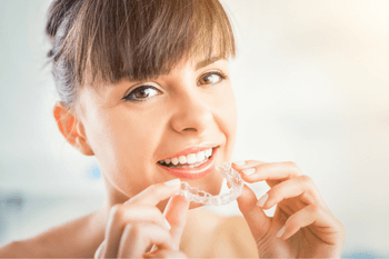 a woman smiling while holding Invisalign braces from our Wolverhampton dental practice
