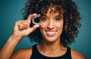 A woman holding Invisalign braces and holding